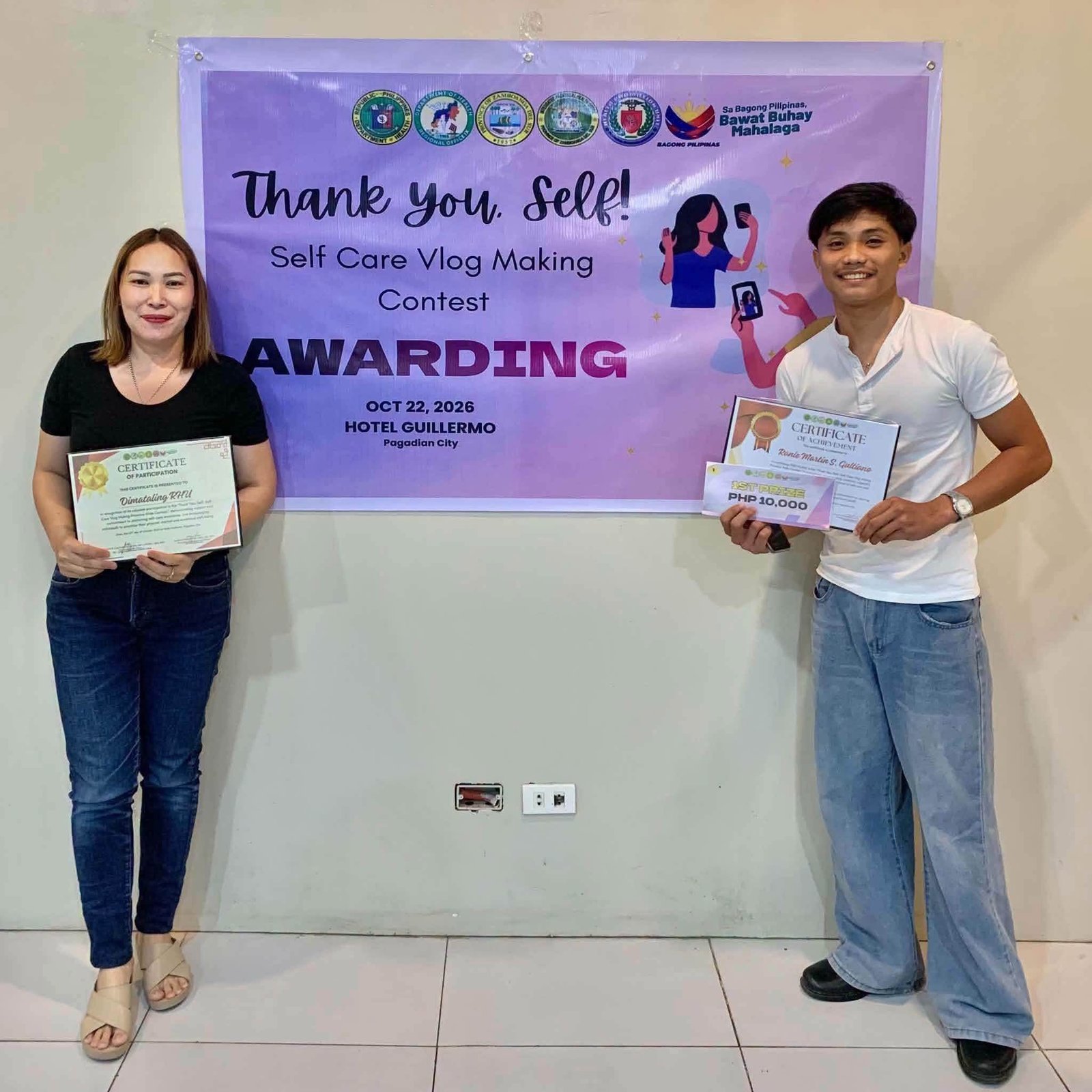 Two award recipients display certificates at the self-care vlog awarding.