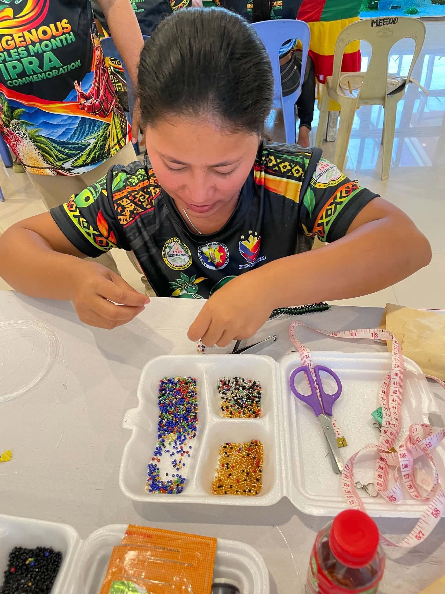 A participant works with coloured beads and craft materials during the Subanen training.